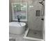 Luxury bathroom featuring a soaking tub, walk-in shower, and elegant tile work by a large window at 5860 Fairway View Dr, Suwanee, GA 30024