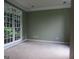 Sunlit living room with neutral walls and carpet featuring a large window with views of greenery at 5860 Fairway View Dr, Suwanee, GA 30024