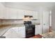 Kitchen with white cabinets, granite countertops, and black gas range at 909 Chapman Cir, Stone Mountain, GA 30088