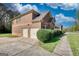 View of home exterior showing a two-car garage, brick facade, and beautifully landscaped yard at 117 Berkeley Way, Hampton, GA 30228