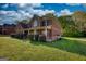 View of the brick home's front, framed by large trees, features a manicured yard and covered porch at 117 Berkeley Way, Hampton, GA 30228
