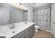Bathroom with double sinks, gray cabinetry, and a shower with a decorative curtain at 935 Amelia Rd, Locust Grove, GA 30248