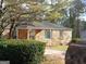 Charming stone house with a well-manicured lawn and a tree with yellow flowers in front at 3249 E Stratton Ln, Scottdale, GA 30079