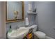 Powder room with sink, toilet, golden framed mirror, and decorative shelf create a stylish space at 1744 Elks Club Rd, Covington, GA 30014