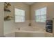 Inviting soaking tub framed by tile with corner windows and a storage area at 1744 Elks Club Rd, Covington, GA 30014