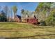 Well-maintained brick home with a covered porch, surrounded by mature trees and a lush green lawn at 1744 Elks Club Rd, Covington, GA 30014