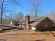 Rear exterior elevation of home, featuring brick chimney and brown roof against bare trees at 3314 Henson Ln, Stockbridge, GA 30281