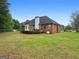 Exterior view of a well-maintained brick home with a large grassy backyard and deck at 205 Wynnfield Way, Mcdonough, GA 30252