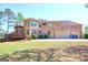 Spacious brick home with a three-car garage and well-maintained lawn, showcasing ample parking and curb appeal at 65 Lotus Ln, Covington, GA 30016