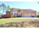 Expansive brick home featuring a deck, three-car garage, and mature landscaping at 65 Lotus Ln, Covington, GA 30016