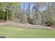 Landscaped backyard featuring retaining wall and mature trees at 100 Smokerise Trce, Peachtree City, GA 30269