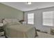 Inviting bedroom features light green wall, a comfortable bed with storage, and plenty of natural light from the two windows at 517 Daffodil Ln, Mcdonough, GA 30253