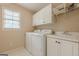 Bright laundry room with a window, white cabinetry, and a utility sink at 7415 Northampton Ct, Cumming, GA 30040