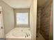 Bright bathroom featuring a soaking tub under a window and a marble-tiled walk-in shower at 210 Huntington Dr, Mcdonough, GA 30253