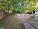 Large backyard space featuring a unique circular patio, mature trees, and partial fence at 240 Carsons Cv, Mcdonough, GA 30253