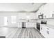 Modern kitchen featuring white cabinets, stainless steel appliances, and grey wood-look floors at 3413 Arabian Farm Ln, Dacula, GA 30019