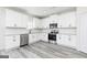 Bright kitchen features white cabinets, stainless steel appliances, granite countertops, and gray wood-look flooring at 3413 Arabian Farm Ln, Dacula, GA 30019