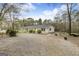 Exterior view of a home with gravel drive, detached garage, and partially wooded lot at 12435 Hamilton Rd # 536/- Ac, Chattahoochee Hills, GA 30268