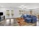 Bright living room featuring wood floors, a blue sectional, and access to the deck at 12435 Hamilton Rd # 536/- Ac, Chattahoochee Hills, GA 30268