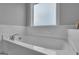 Soaking tub with marble backsplash and trim, large faucet, and frosted window at 176 Butler Rd, Brooks, GA 30205