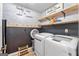 Laundry room features a brick accent wall, wooden shelves and modern washer/dryer units at 105 Honey Creek Rd, Mcdonough, GA 30252