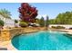 An in-ground pool features stone edging, small waterfall and lush landscaping at 155 Duncans Mill Dr, Locust Grove, GA 30248
