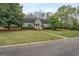 Home with a well-manicured lawn, mature trees, and a charming red front door at 6140 Ginn Se St, Covington, GA 30014