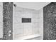 Detailed shower space includes black river rock accents and neutral tiling with built-in shelf at 70 Barrington Farms Ct, Sharpsburg, GA 30277