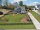 Aerial view of a beautiful home with a manicured lawn and driveway, surrounded by a black wooden fence at 108 White Oak Tl, Cumming, GA 30028