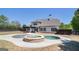 Backyard view of a white two-story home with an outdoor kitchen, patio, and custom pool with a hot tub at 1 Red Oak Trl, Sharpsburg, GA 30277