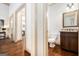 Hallway leading to a bathroom featuring a wood vanity with dark granite countertops, and decorative mirror at 1 Red Oak Trl, Sharpsburg, GA 30277