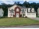 Charming two-story home featuring a brick facade, three-car garage, and lush front lawn at 1592 Smithson Ct, Lithonia, GA 30058