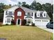 Charming two-story home featuring a brick facade, three-car garage, and lush front lawn at 1592 Smithson Ct, Lithonia, GA 30058