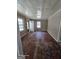 Living room with two windows, aged hardwood floors, and an open front door at 1243 Hill Nw St, Conyers, GA 30012