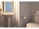 Cozy half bathroom featuring a pedestal sink, mirror, toilet, and gray walls at 75 Prestwick Ln, Peachtree City, GA 30269