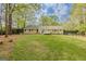 Wide backyard with a lush lawn and views of a home with a deck, surrounded by mature trees at 115 Bob White Trl, Fayetteville, GA 30215