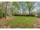 Serene backyard with a green lawn, mature trees, and a charming storage shed at 115 Bob White Trl, Fayetteville, GA 30215