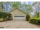 Attached two-car garage with white door and siding, surrounded by mature landscaping at 115 Bob White Trl, Fayetteville, GA 30215