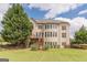 Expansive backyard with lush lawn, mature trees, tiered wood deck, and multi-story traditional home at 217 Brunswick Dr, Tyrone, GA 30290