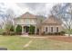 Grand two-story brick home with a covered balcony, columned entryway, and professionally landscaped front yard at 217 Brunswick Dr, Tyrone, GA 30290