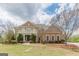 Elegant brick home featuring a covered balcony, manicured shrubs, and a lush green lawn at 217 Brunswick Dr, Tyrone, GA 30290