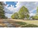 Spacious green space showcasing a walking path, mature trees, and the community clubhouse in the distance at 217 Brunswick Dr, Tyrone, GA 30290