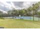 Community tennis courts surrounded by a fence and trees, with court benches and lighting at 217 Brunswick Dr, Tyrone, GA 30290