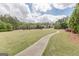 Spacious manicured lawn area with a walking path, trees, and homes on a sunny day at 217 Brunswick Dr, Tyrone, GA 30290