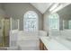 Bright bathroom with vaulted ceiling, arched window, soaking tub, separate shower, and double vanity at 5003 Samantha Ct, Mcdonough, GA 30252