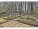 Landscaped backyard with stone retaining wall, fence, and access to wooded area at 35 Ryans Ct, Sharpsburg, GA 30277