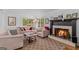 Cozy living room featuring a fireplace with lit fire, comfortable seating, and a stylish patterned rug at 205 Raintree Bnd, Peachtree City, GA 30269