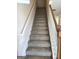 Carpeted staircase featuring a modern wood and white banister leading to upper level at 661 Outlook Way, South Fulton, GA 30349