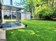 View of backyard featuring lush green grass, a storage shed, screened-in porch and mature landscaping at 1475 Woodington Cir, Lawrenceville, GA 30044