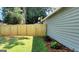 View of backyard with a brand new wooden fence, manicured lawn, and exterior of home with green siding at 1475 Woodington Cir, Lawrenceville, GA 30044
